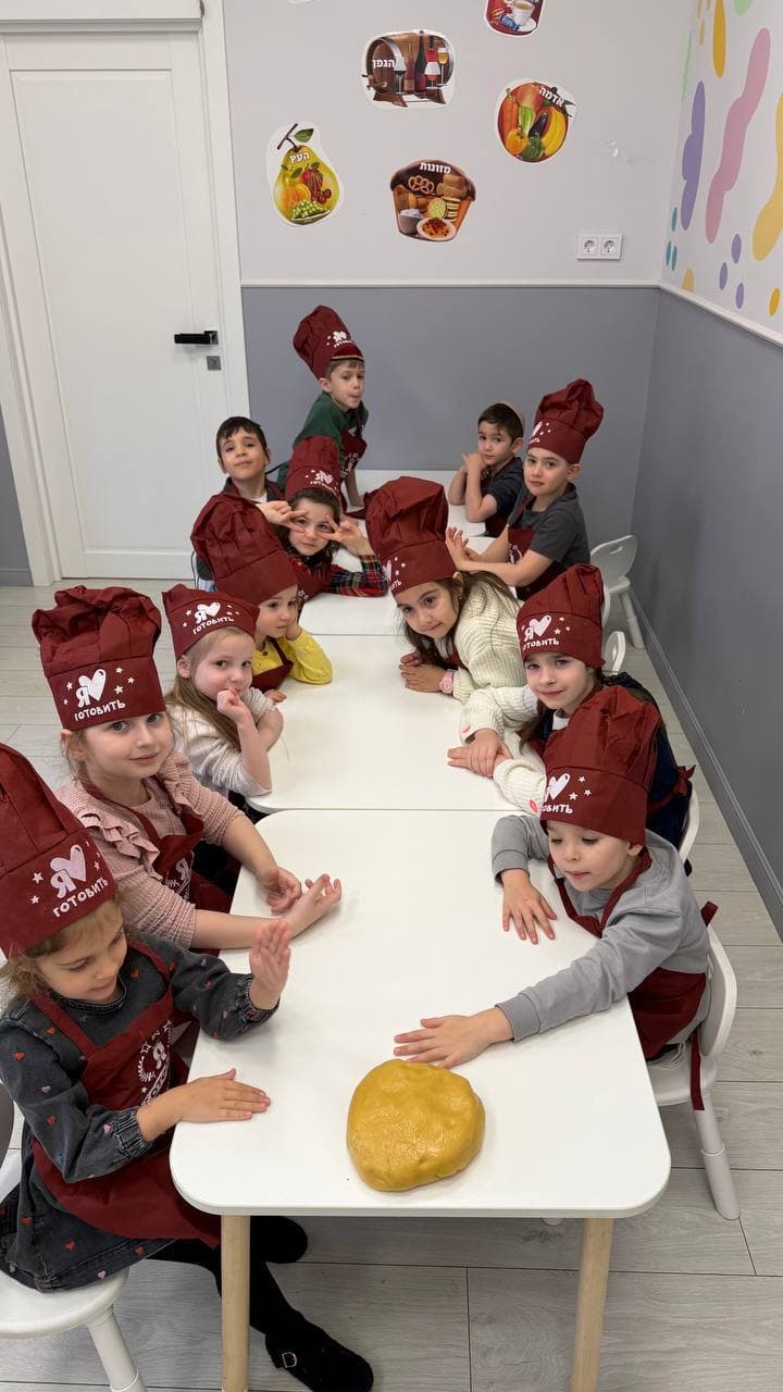 Дети в поварских колпаках готовят тесто