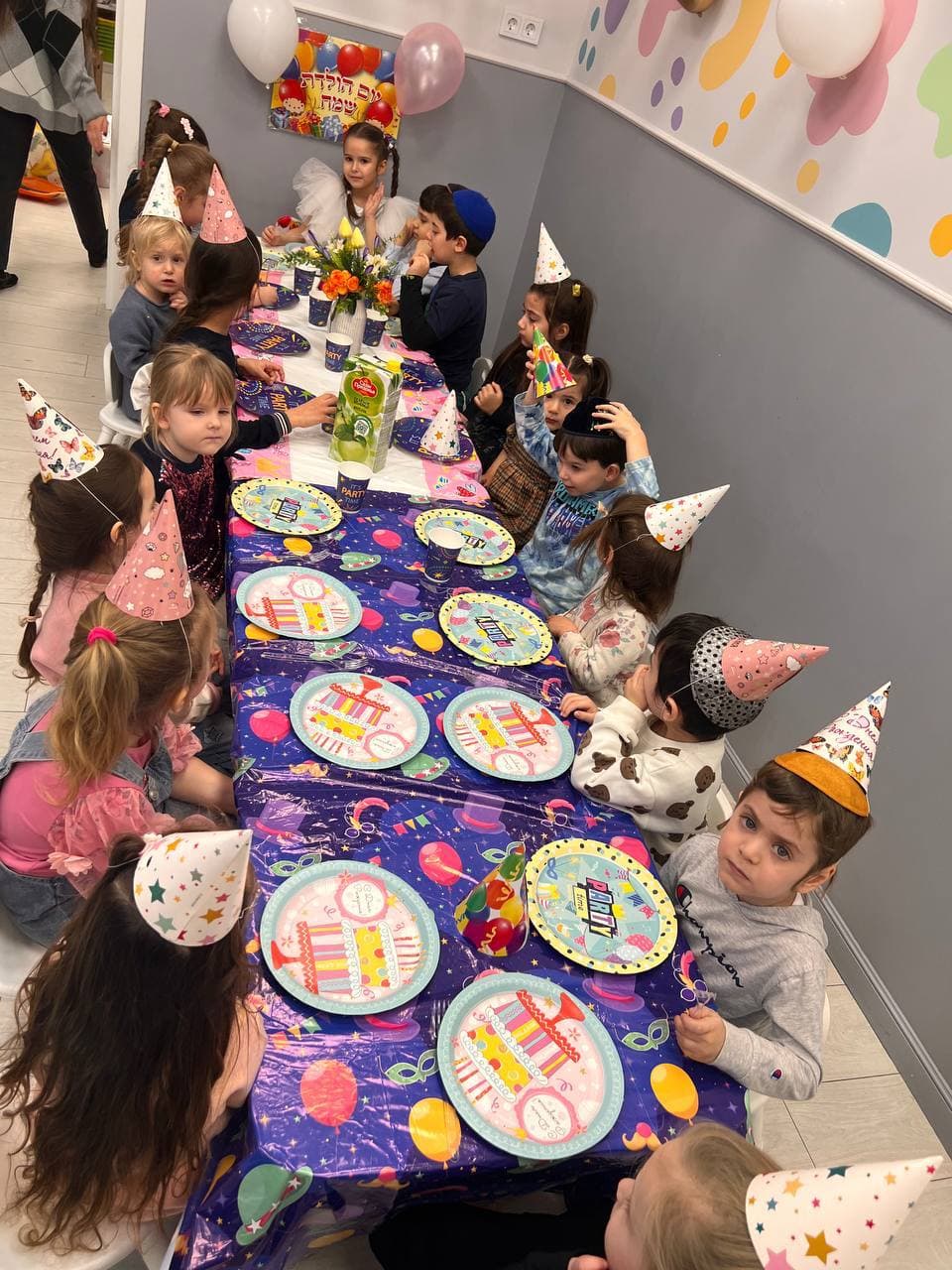 Праздничный стол и дети в колпачках на дне рождения