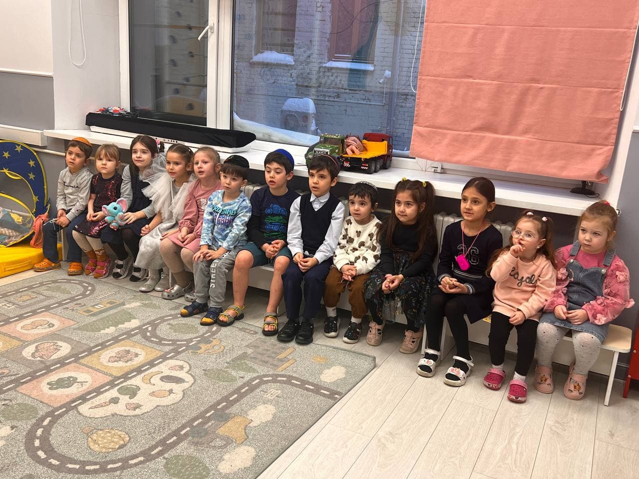 Дети сидят в ряд и слушают педагога перед занятием